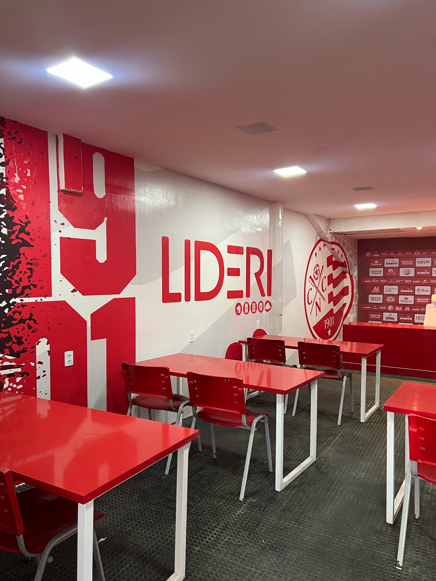 Sala de imprensa do Clube Náutico Capibaribe com painel da marca LIDERI ao lado do escudo do clube